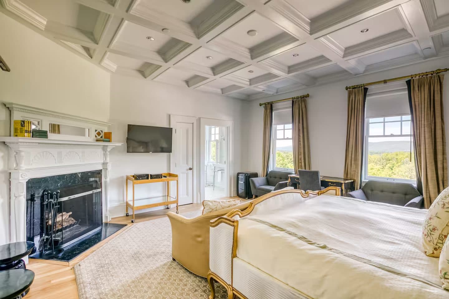 A coffered-ceiling primary suite with a marble fireplace and window nook