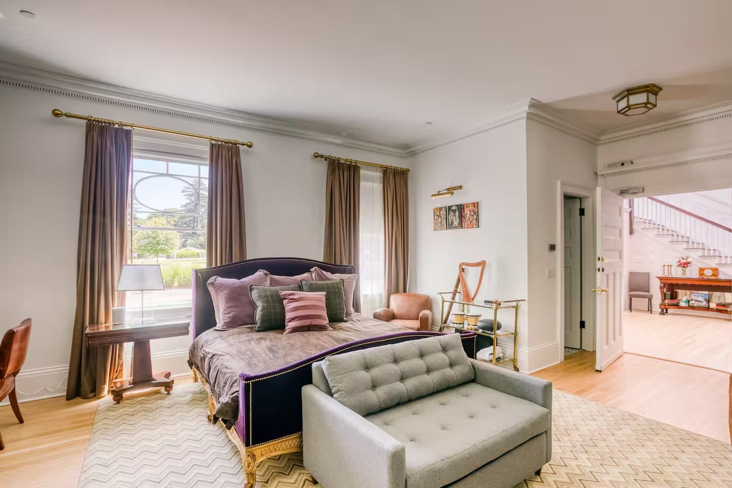 A warm bedroom with an upholstered bed and sunny sitting area