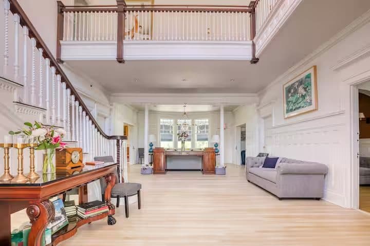 The light-filled grand foyer with a flower-topped console and sweeping staircase
