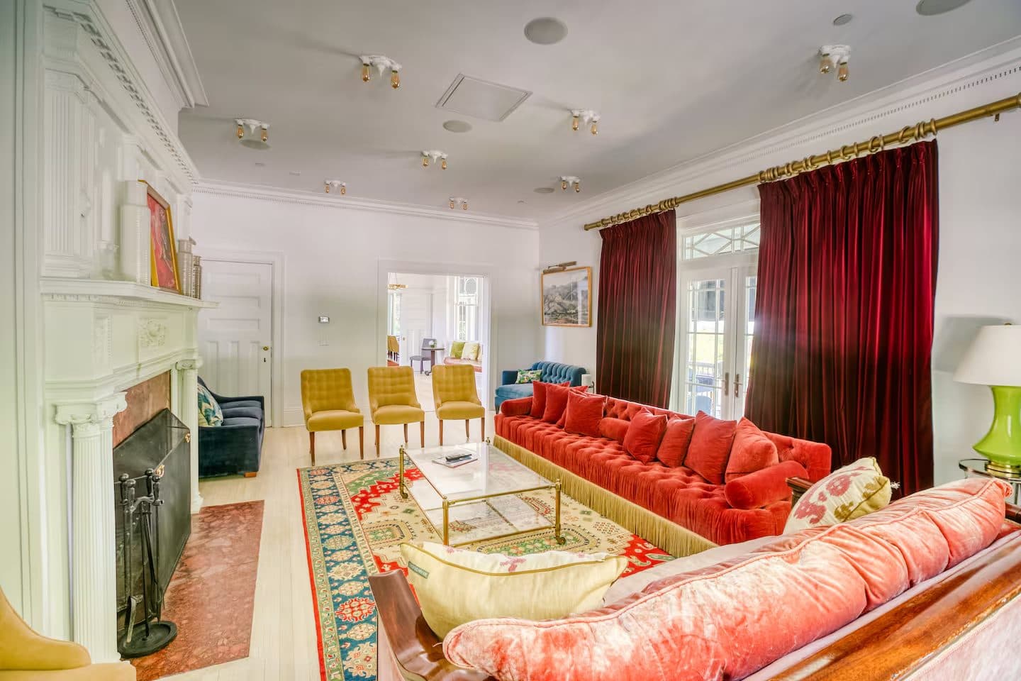 The great room with a marble fireplace, coral sofas and velvet drapery