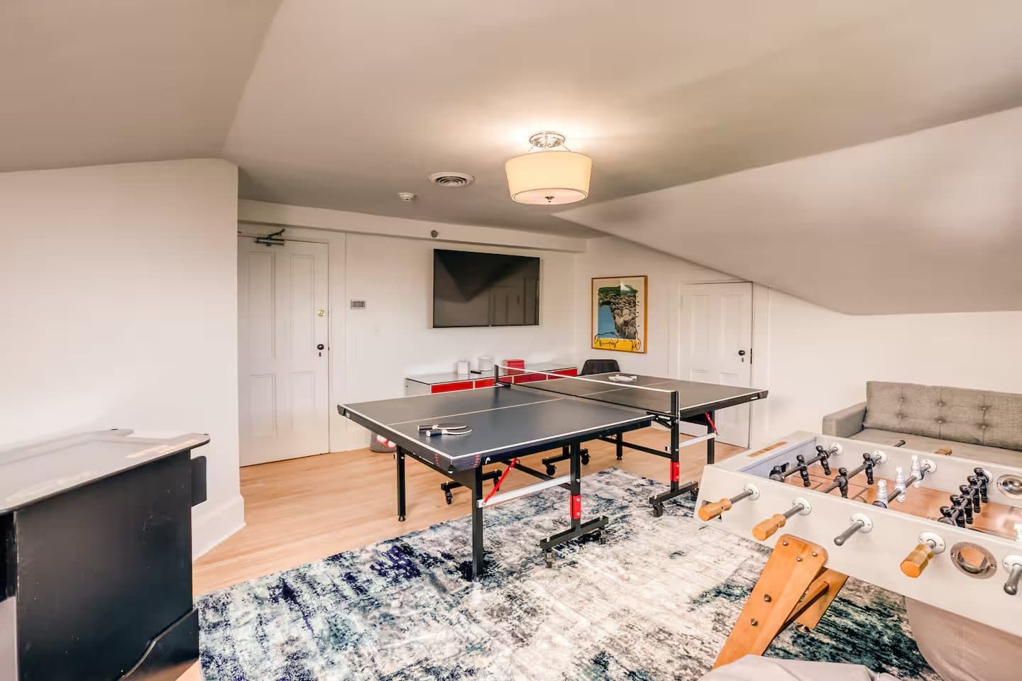 The Game Room with a ping-pong table, foosball and a sofa